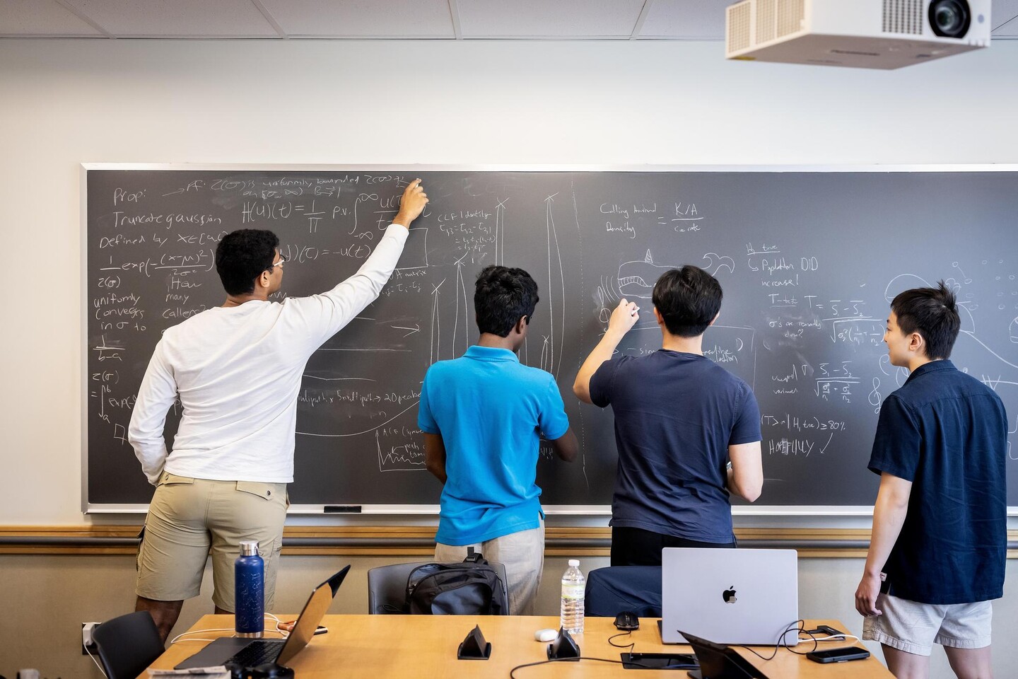 Four undergraduates writing on a blackboard.
