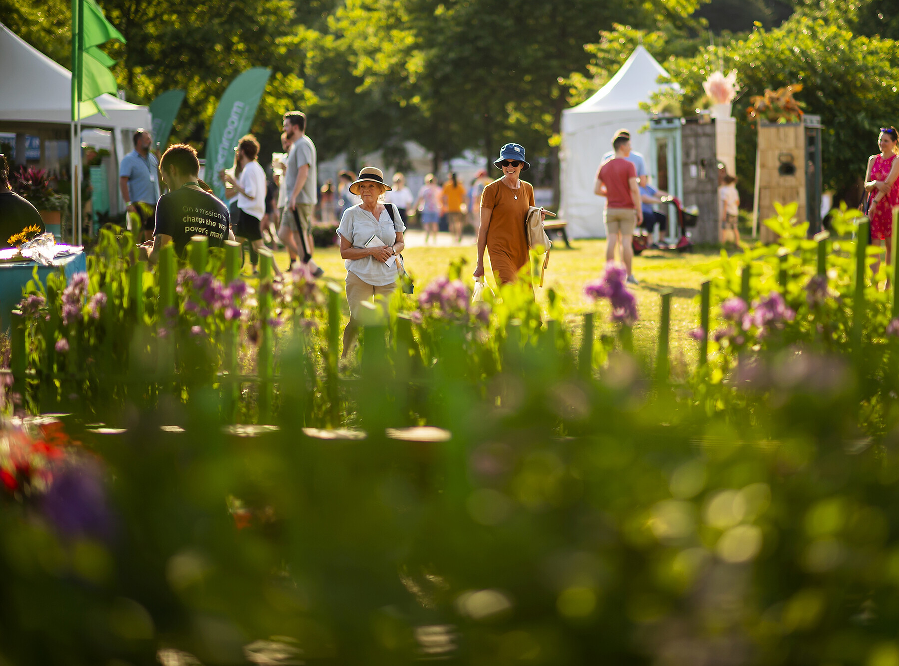 Flower Show onlookers observe flower arrangements.