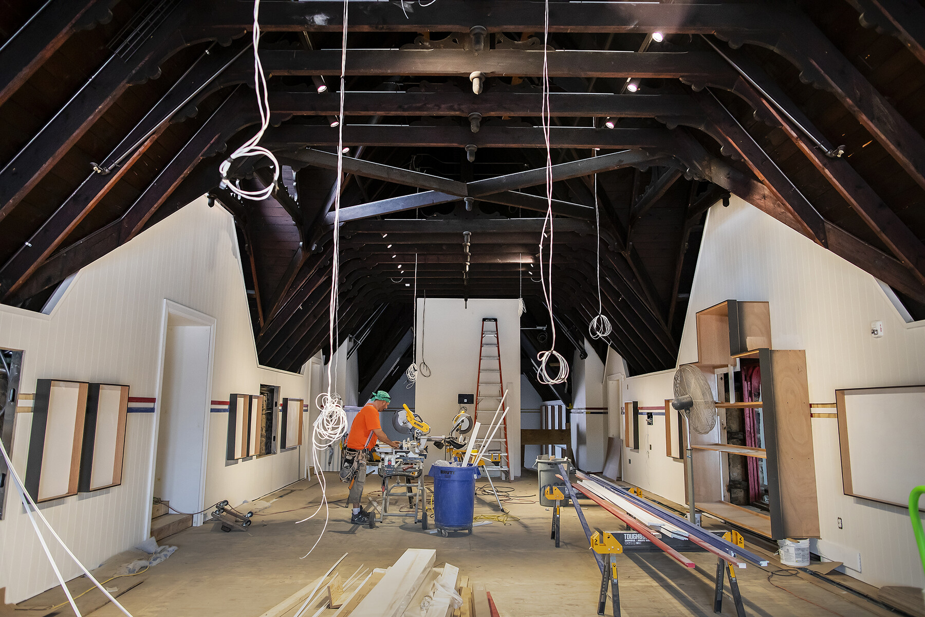 The Great Hall of the Penn Boathouse under construction, a construction worker stands working in the hall.