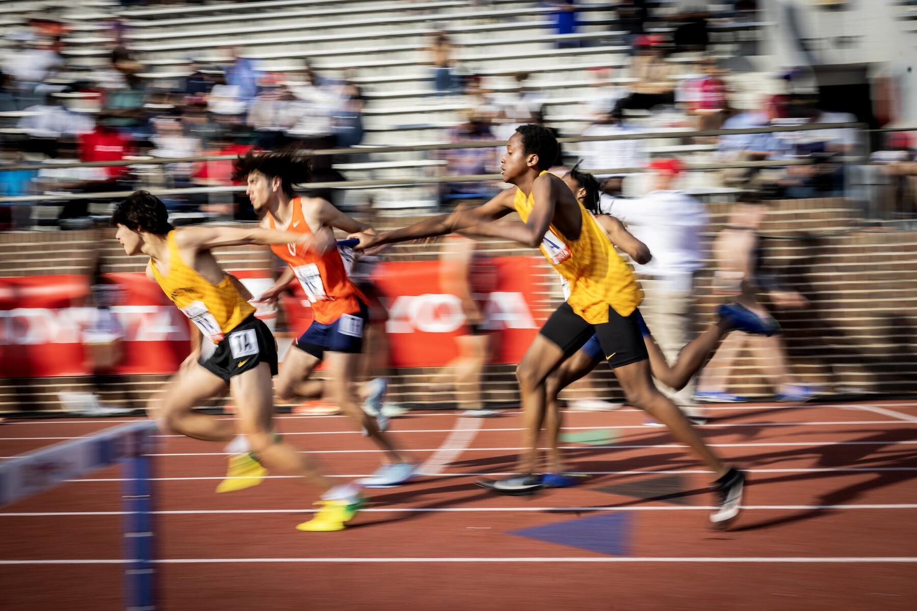 Runners doing a baton handoff during the Penn Relays.