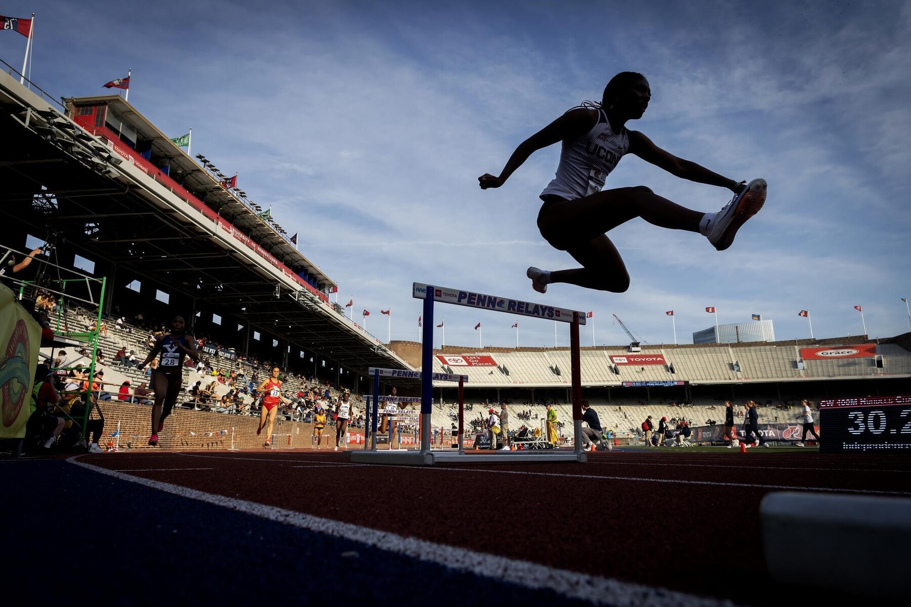 A runner in mid-jump over hurdles at the Penn Relays