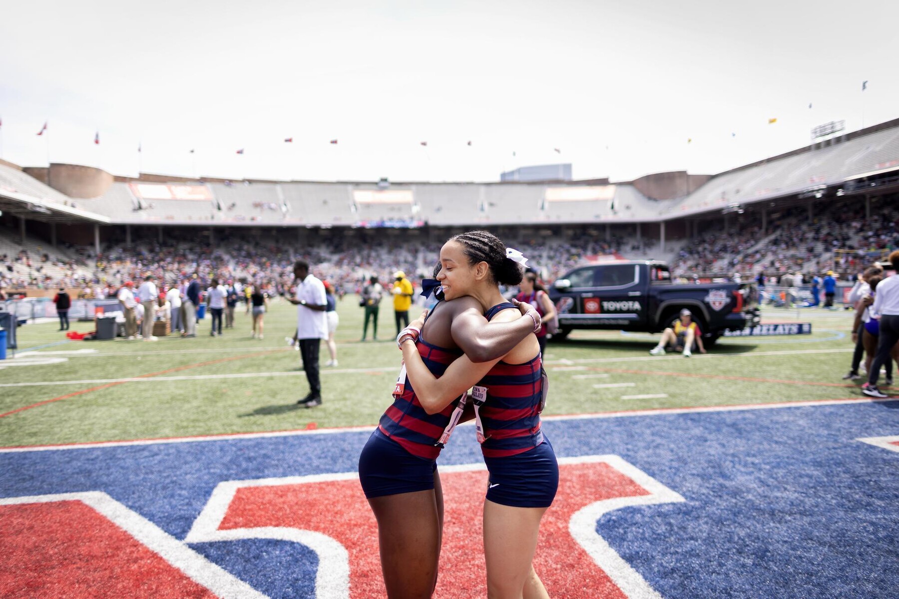 Two Penn Quakers hugging on field at the Penn Relays.