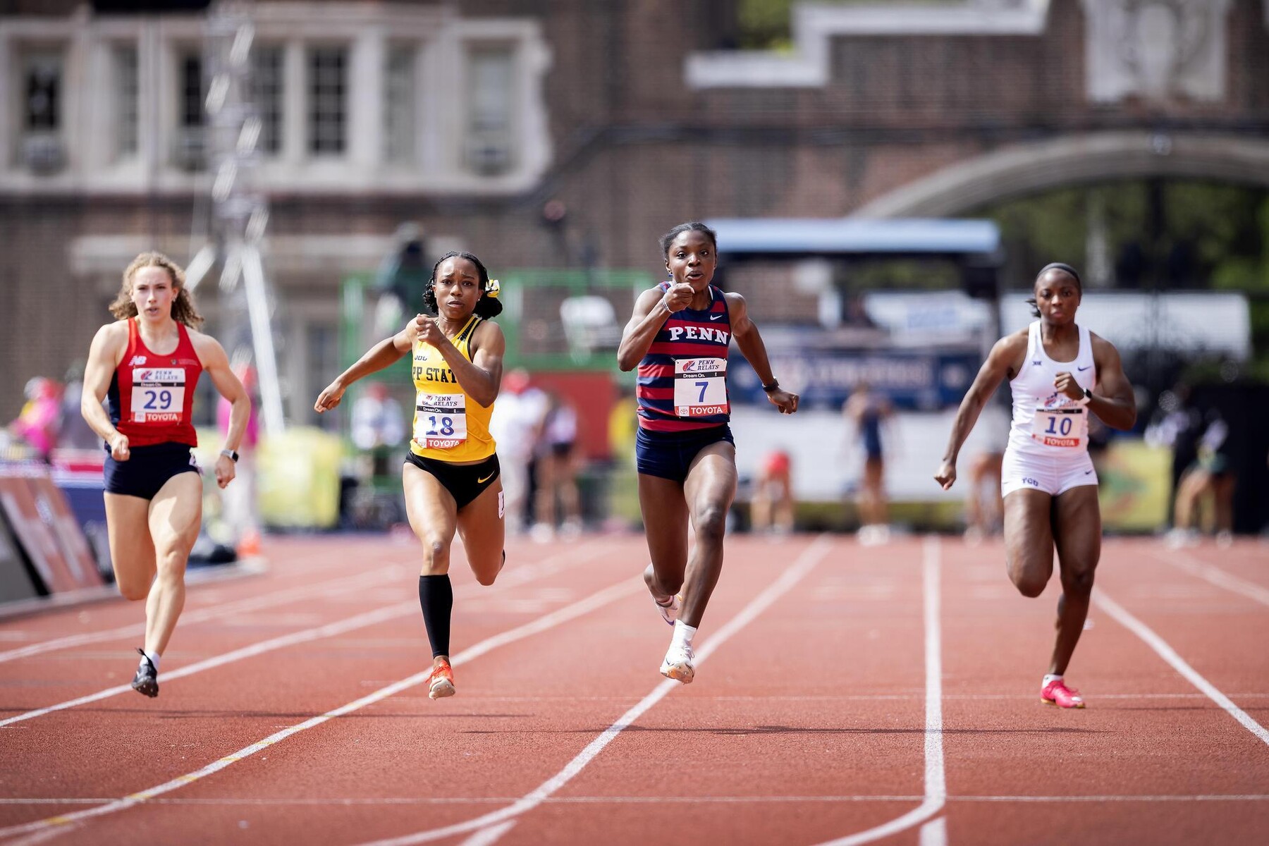 Runners running on the track at Franklin Field during the Penn Relays.