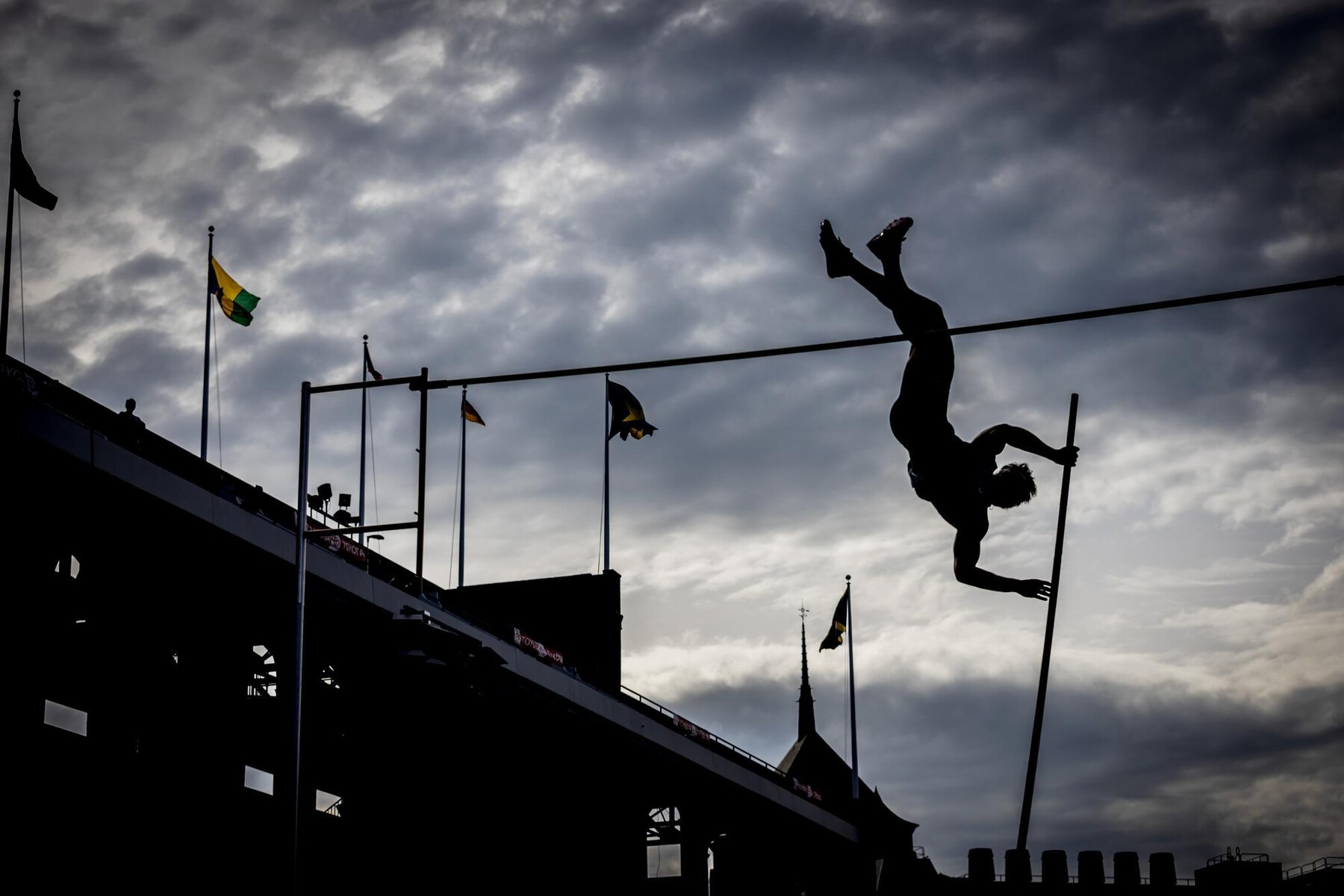 A pole vaulter in mid-jump before the apex of the pole at the Penn Relays.