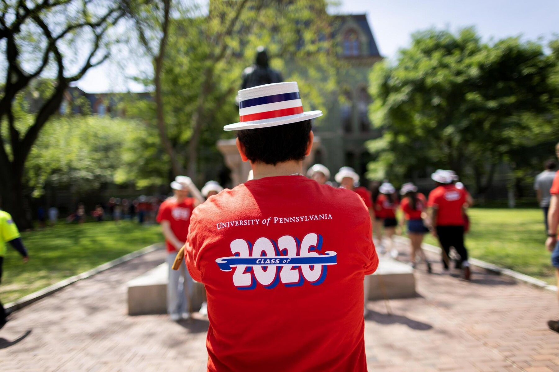 A student on College Green wearing a Hey Day t-shirt and hat.