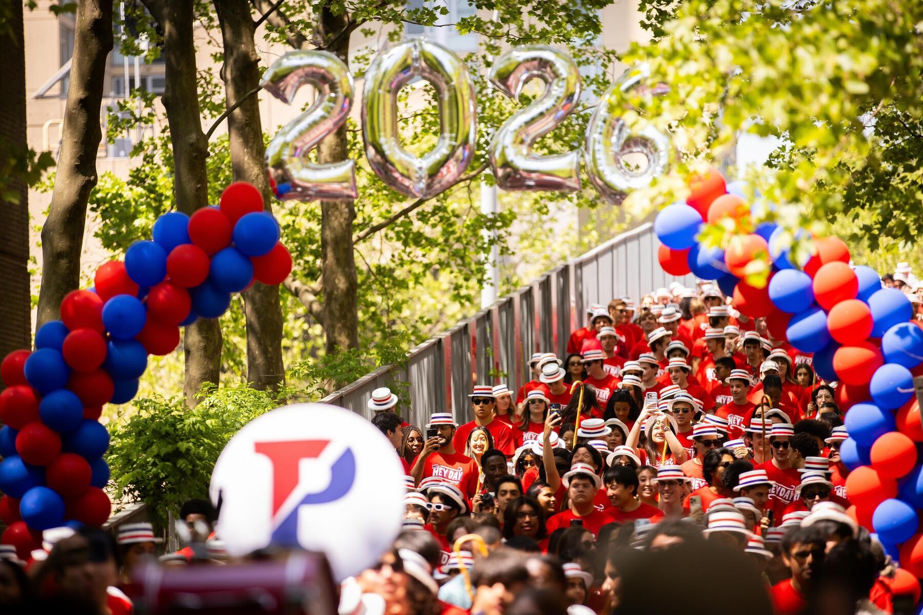 Students walking under a 2026 balloon banner on Locust Bridge during the Hey Day procession.