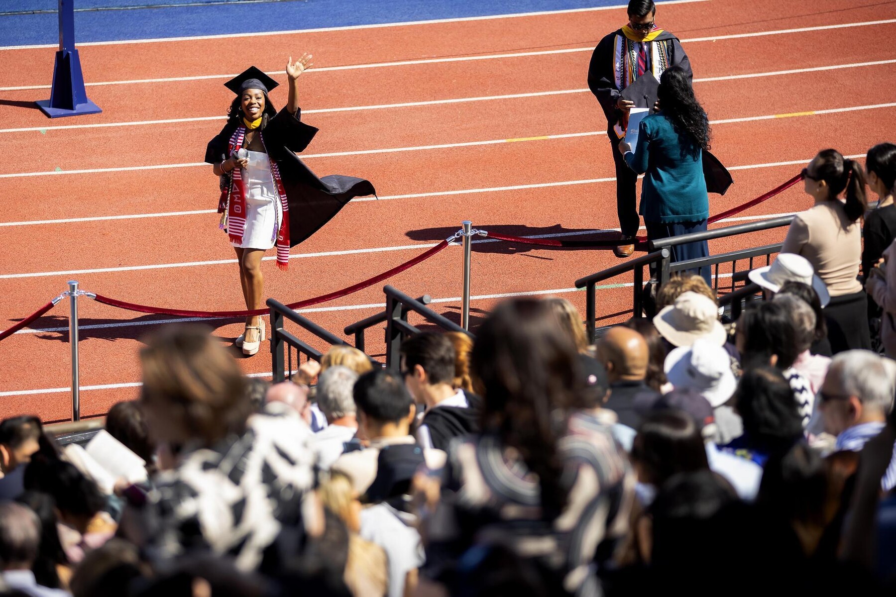 A student on Franklin Field waves to the crowd at Penn’s Commencement.