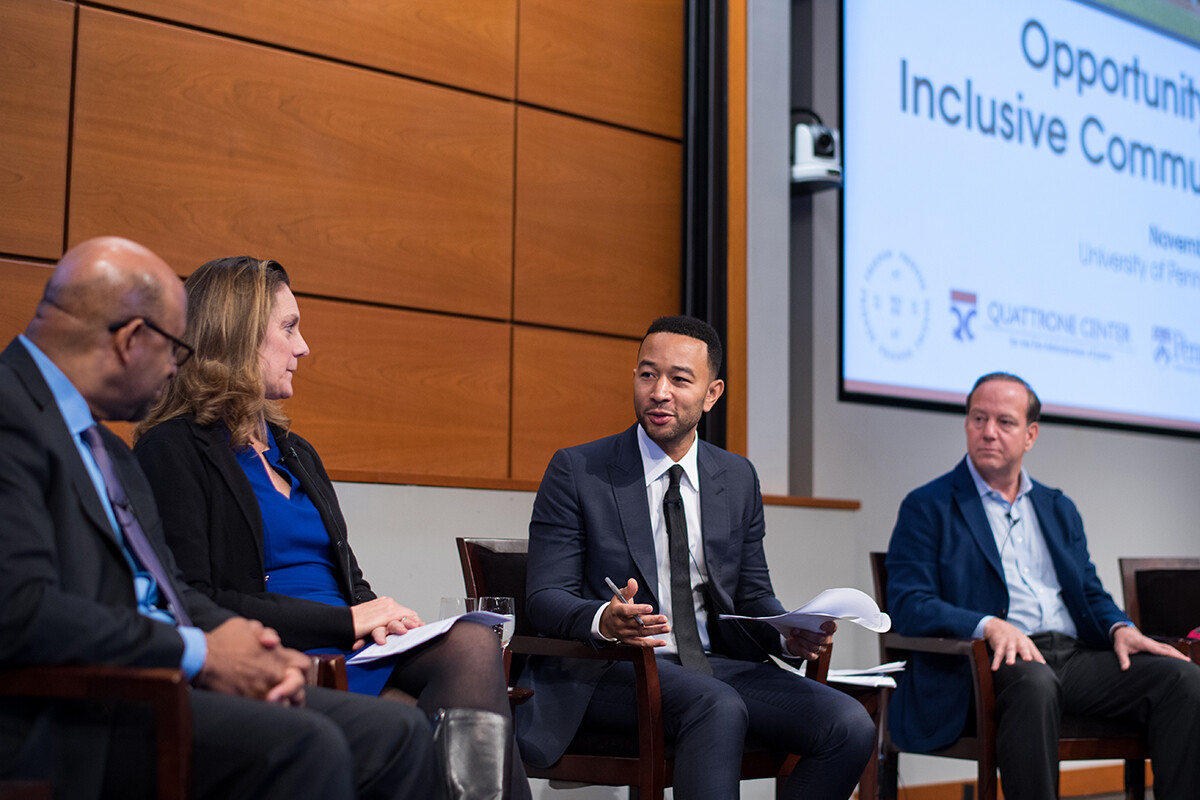 Four people sit on stage for a panel discussion on opportunity zones.