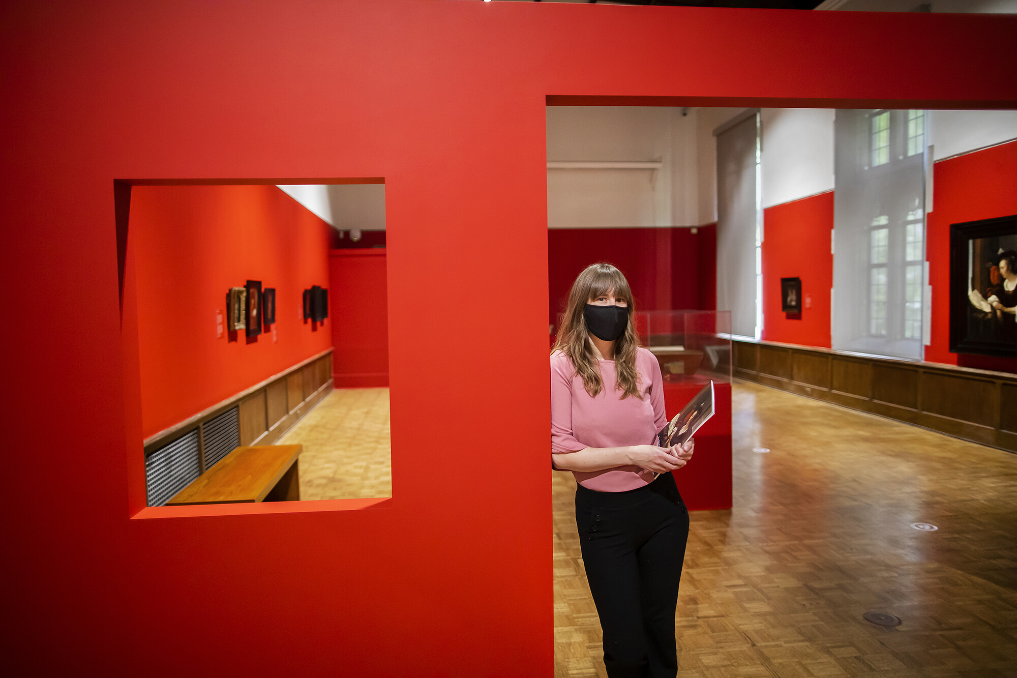 woman standing in doorway of art gallery with paintings on the walls
