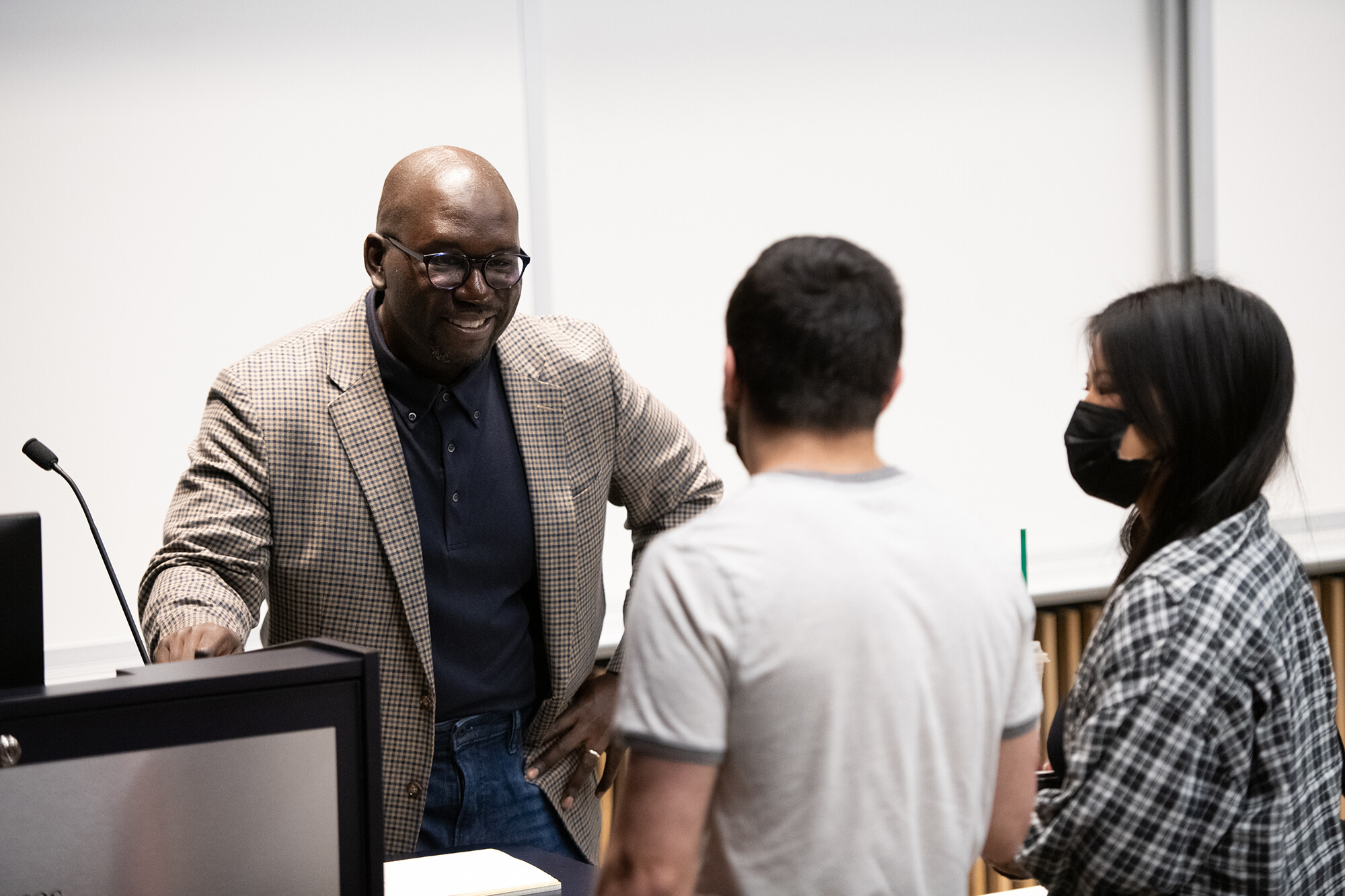 Jamelle Bouie smiles as two students speak to him.
