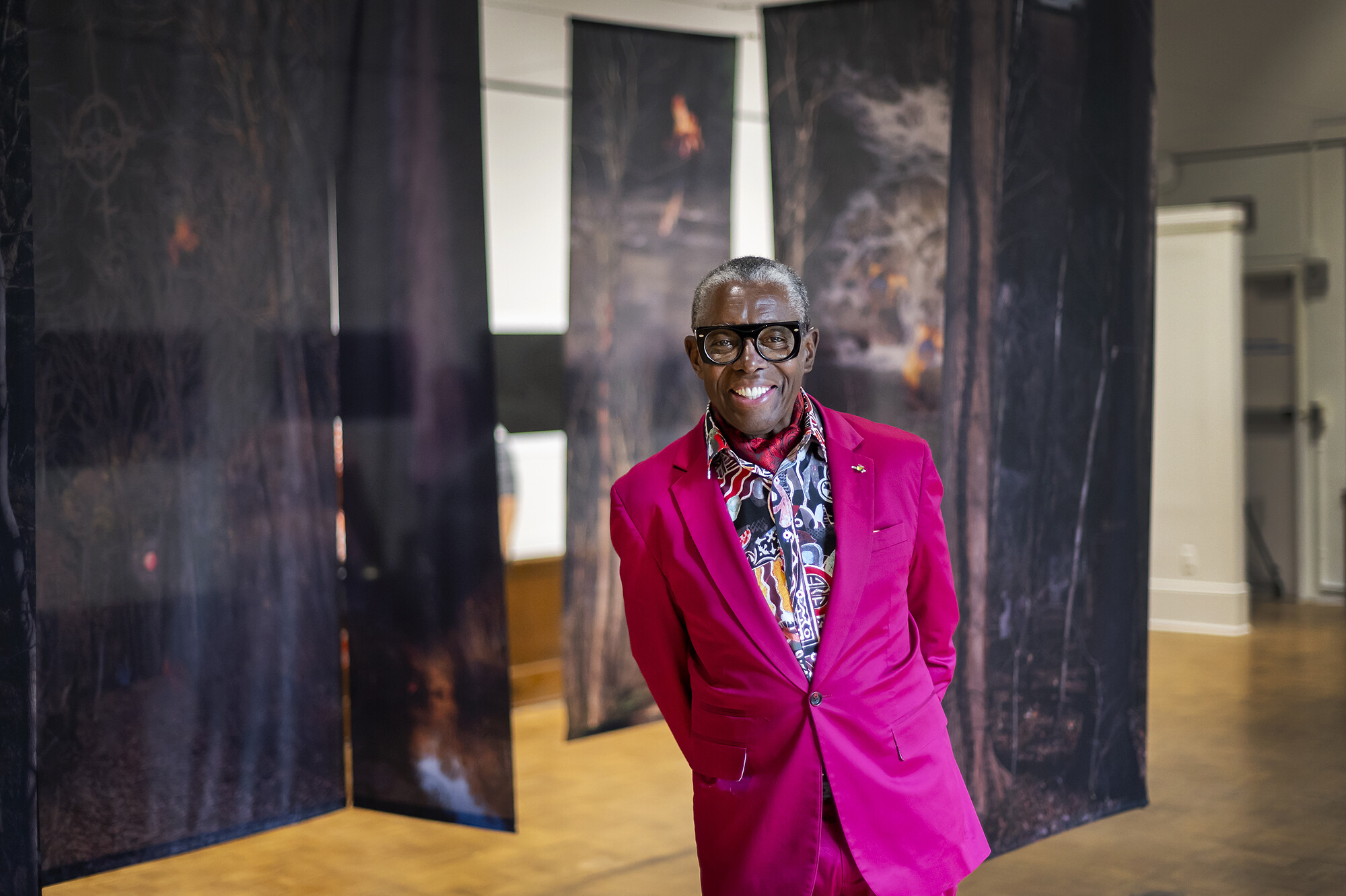 artist John Dowell standing in center of Arthur Ross Gallery with fabric panels hanging behind him 