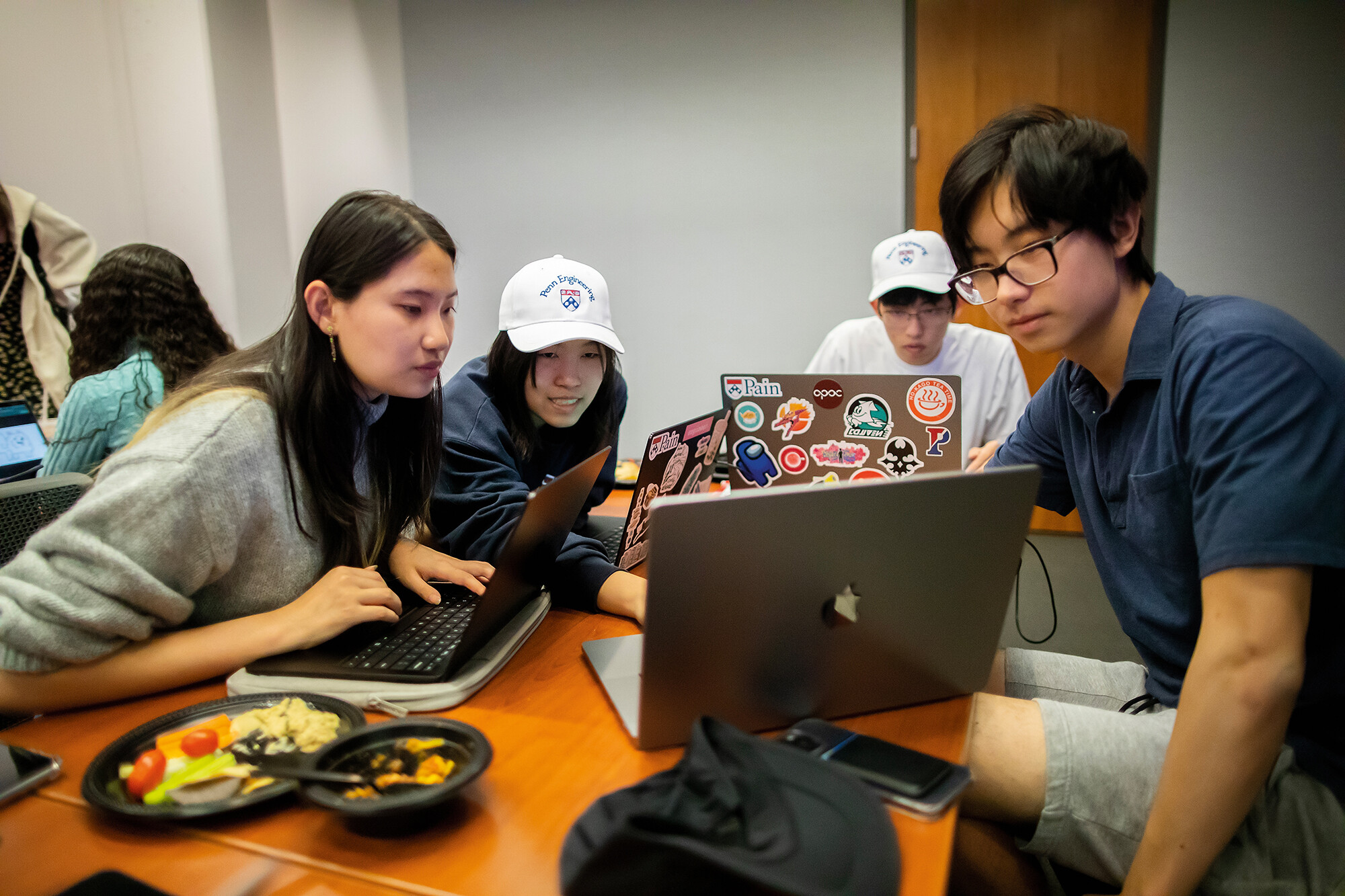 Four students looking at laptops working together as a team.