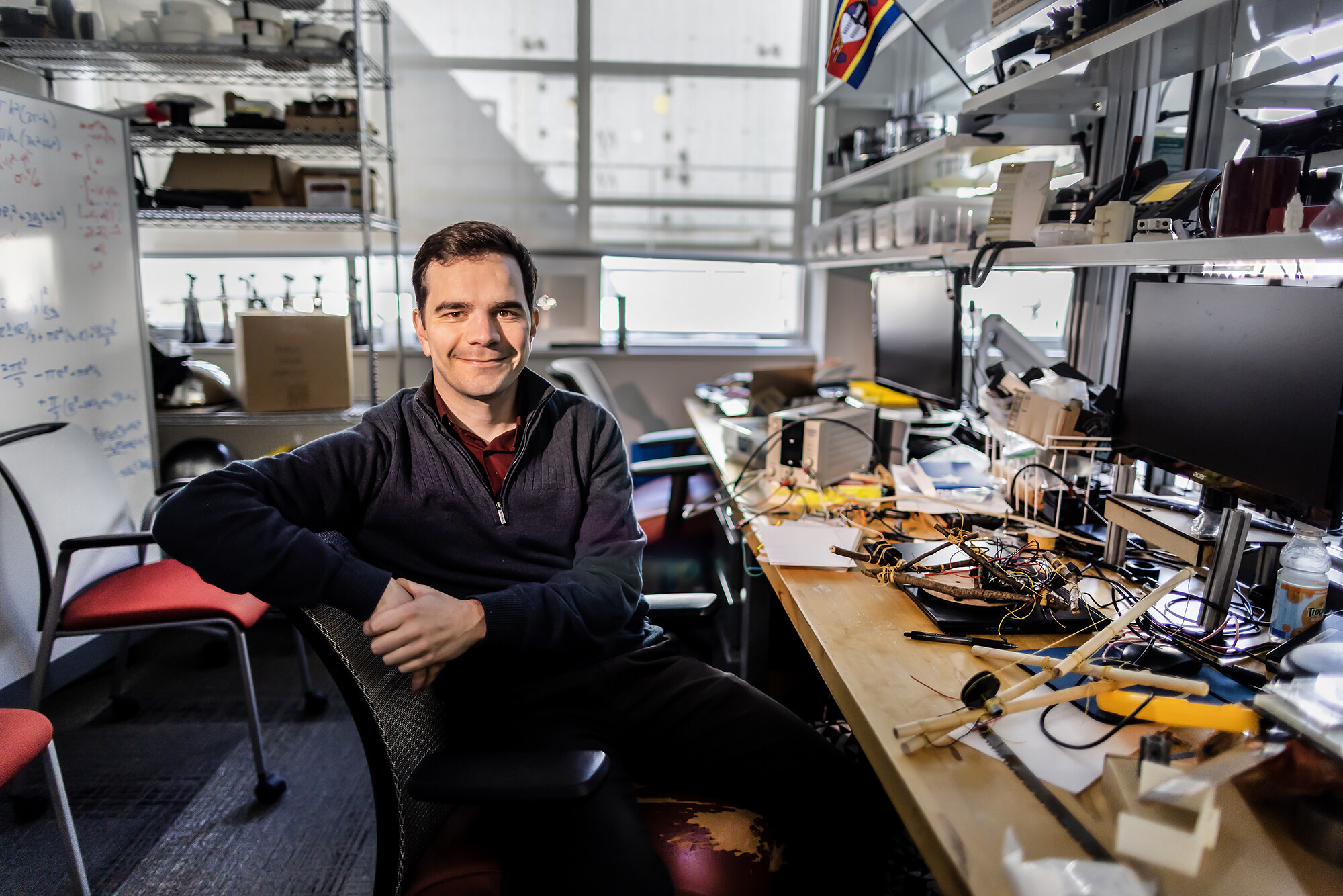 Devin Carroll sits at his desk, which is strewn with bits and pieces from his robots.