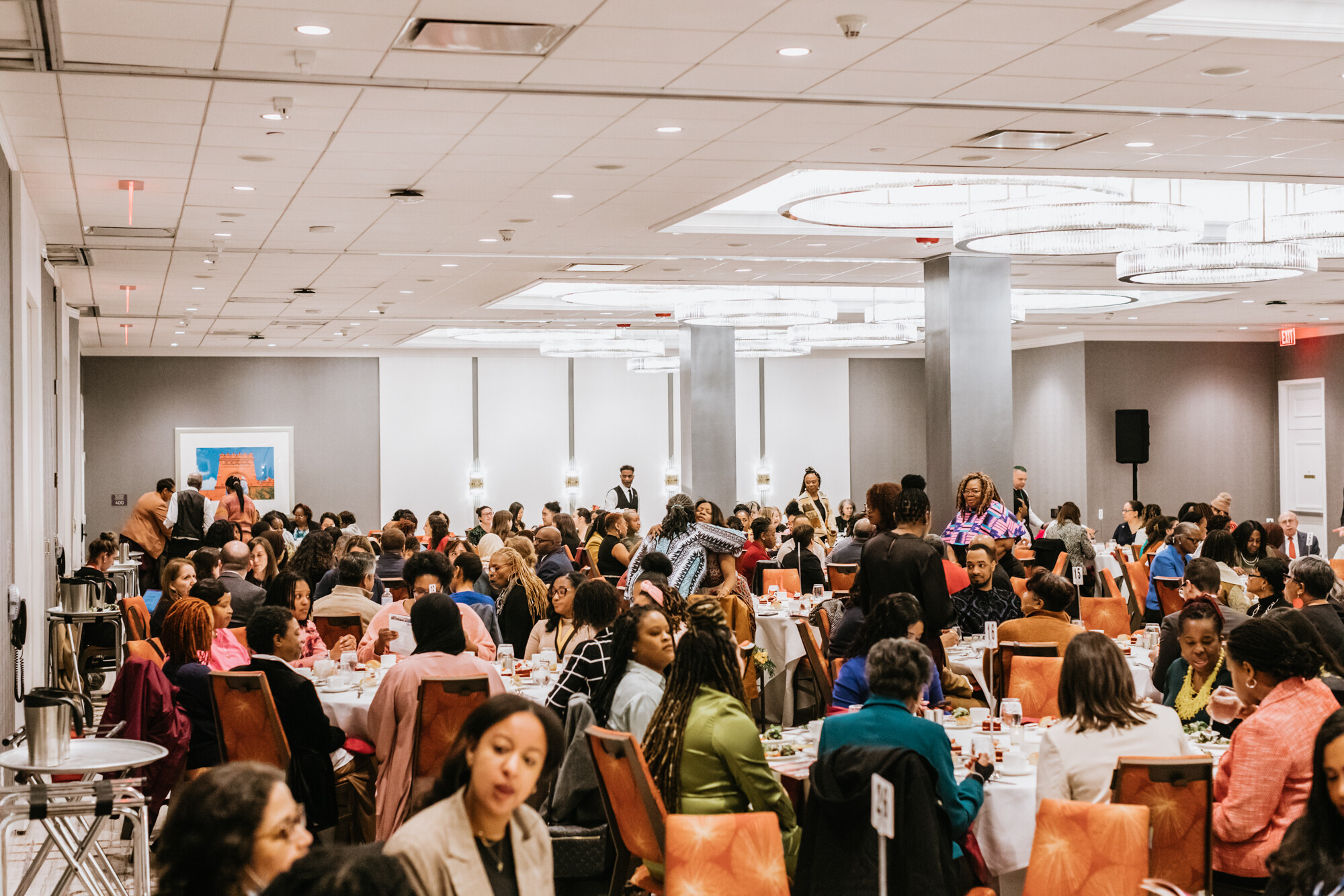 Multiple round tables of ten clustered in a hotel ballroom. 