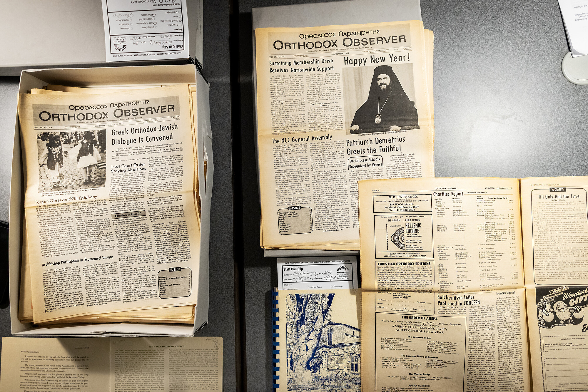 Flatlay of boxes filled with yellowing newspapers from the Orthodox Observer