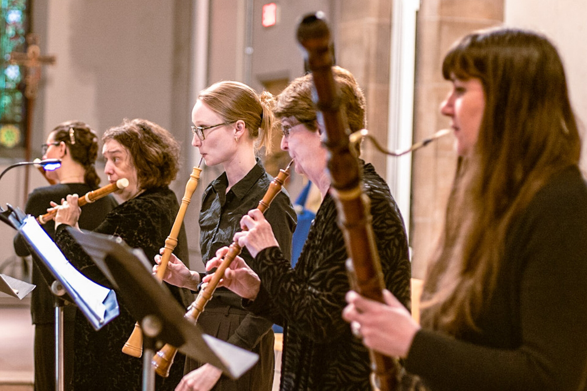 five musicians standing and playing wind instruments