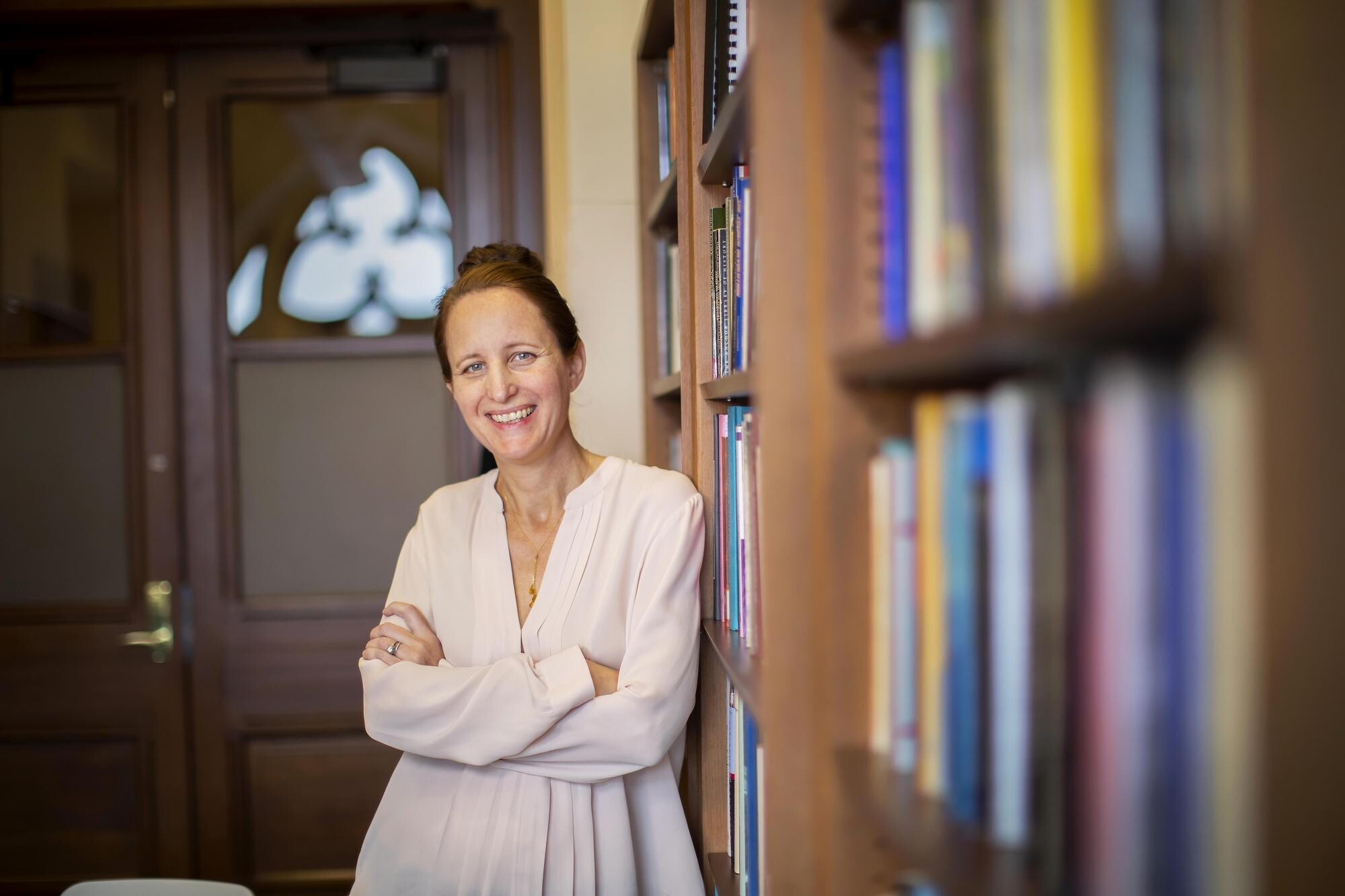 Sophia Rosenfeld leans against a bookshelf smiling.