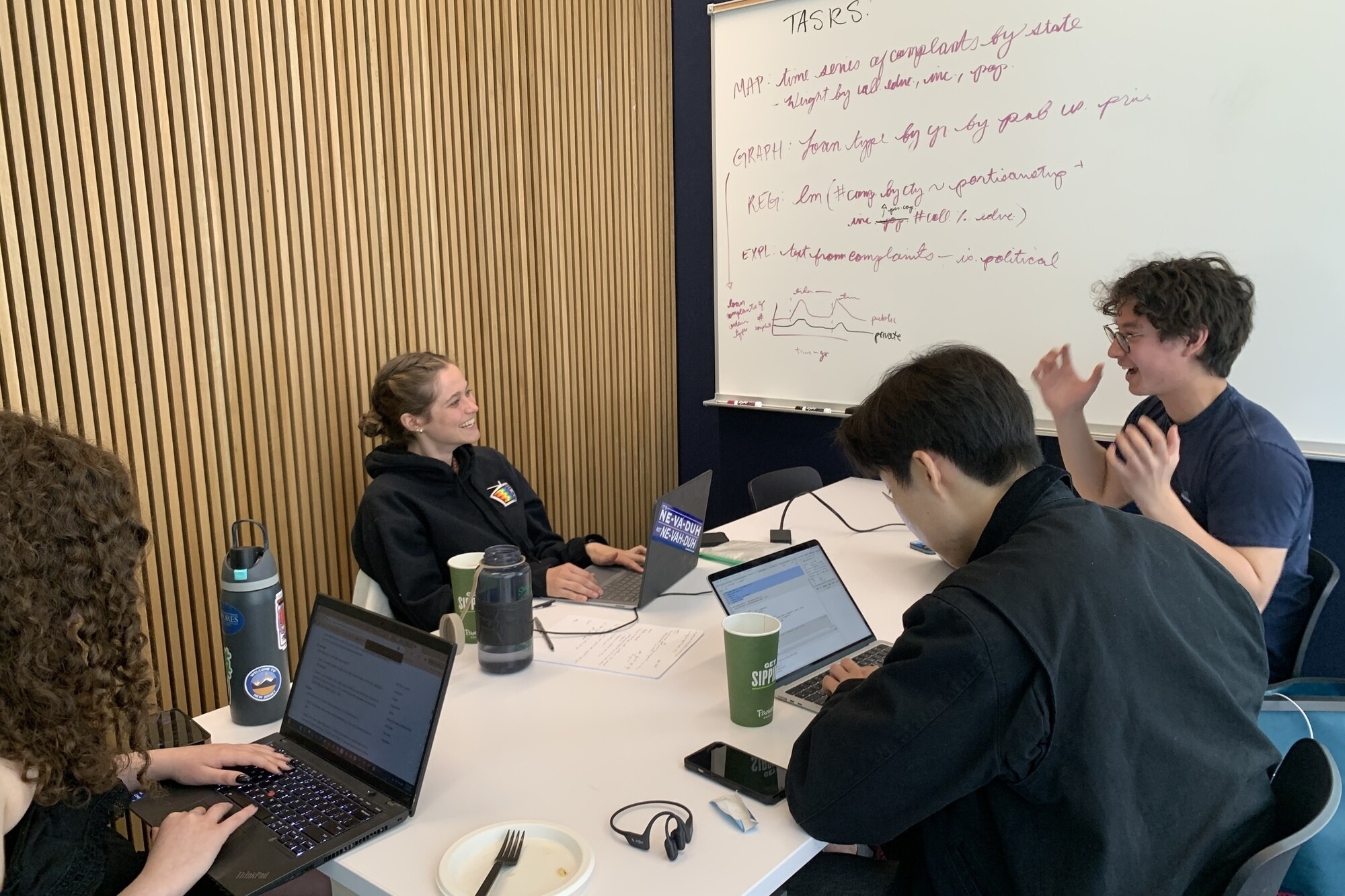 Jackie Balanovsky, Glynn Boltman, Ki Joon Lee, and Geddy Lucier sit around a table working on their laptops.