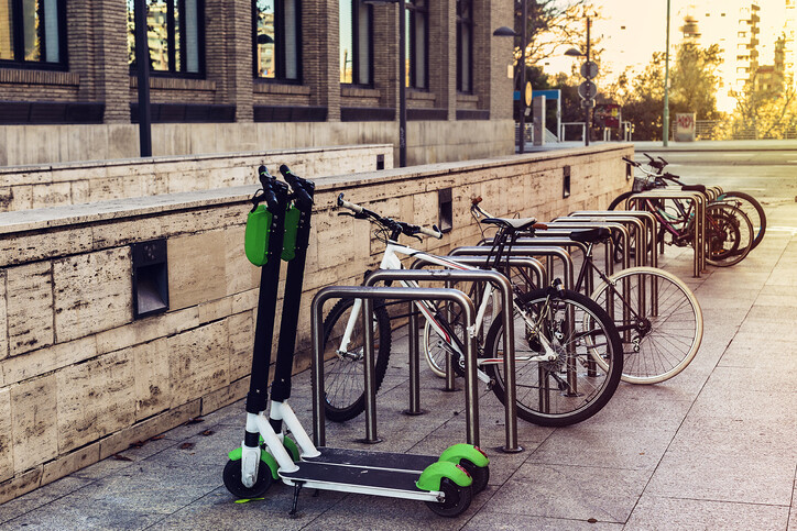 two scooters parked next to a bike rack with bikes parked on a sidewalk