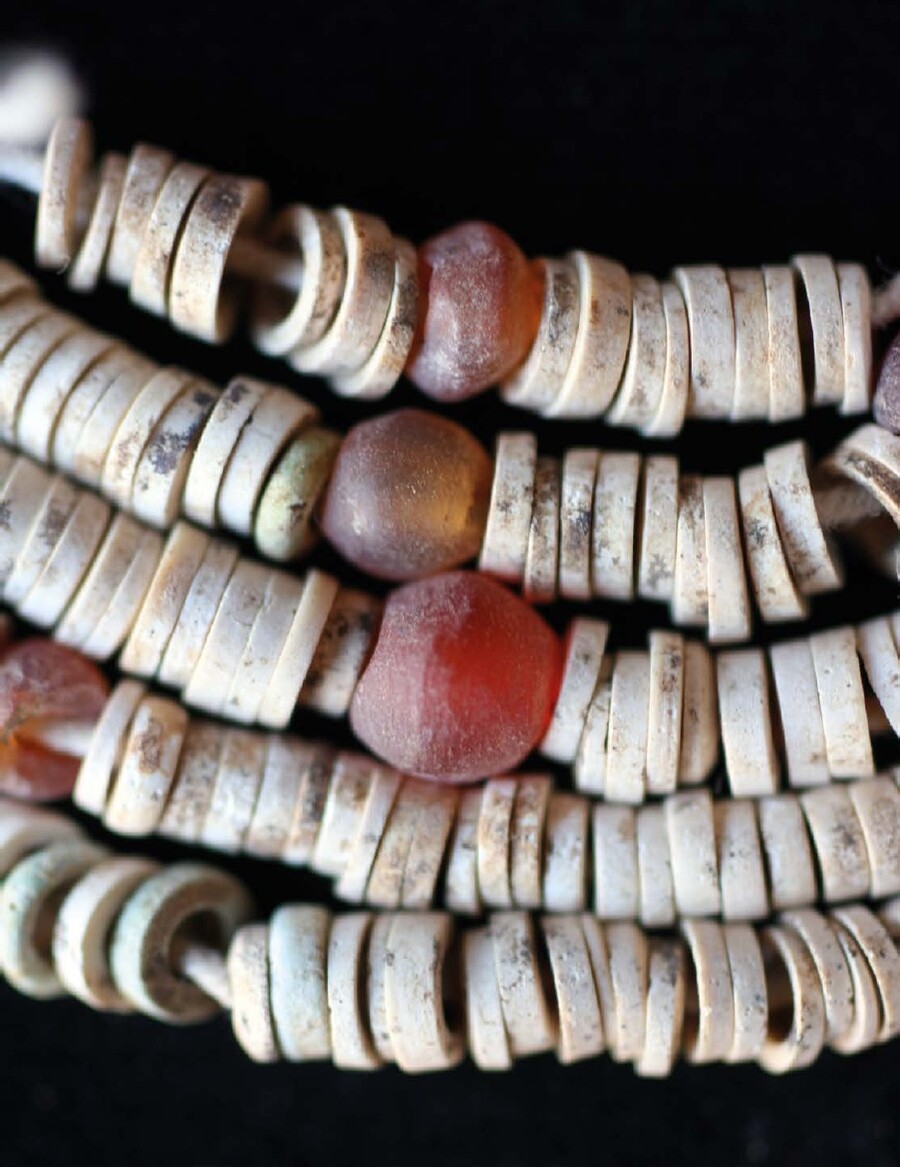 Four rows of white-beaded jewelry with red beads mixed in. 