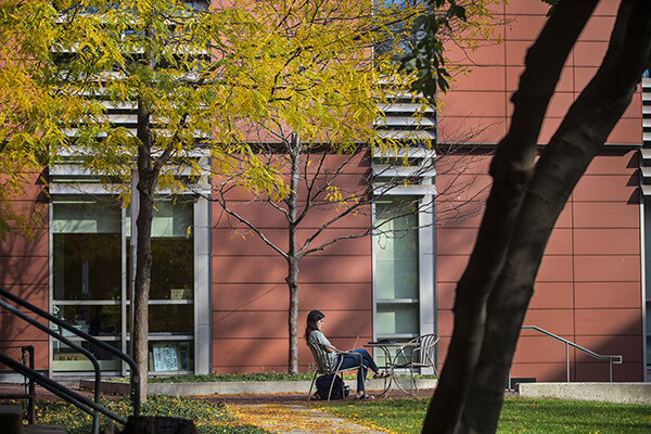 person sitting outside on Penn's campus at a table in the daylight with a laptop in their lap