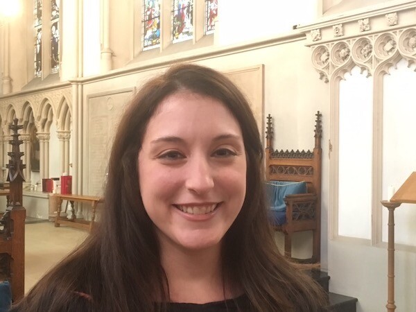 Headshot of person inside an old church smiles at the camera.