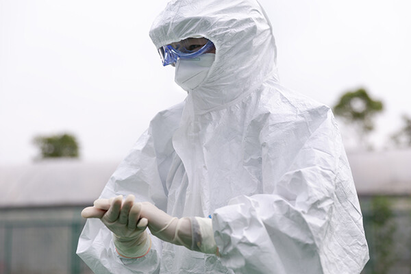 Health care personnel in full PPE rubbing their gloved hands.