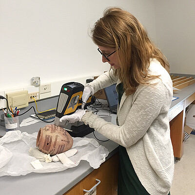 Charlotte Tisch drills into an artifact that resembles a medium-sized vessel.