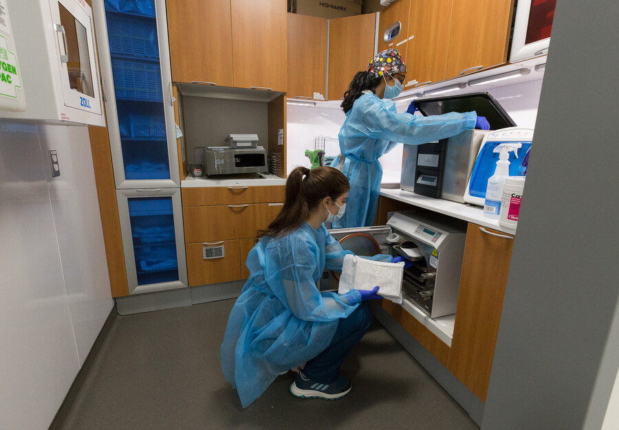 Two dental students get equipment ready in a dental clinic