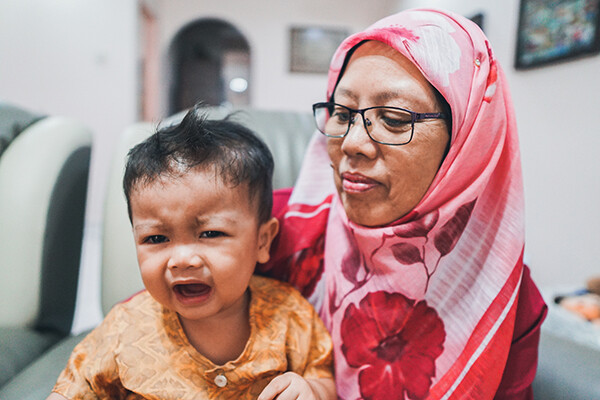 Muslim grandparent holding a distressed child.