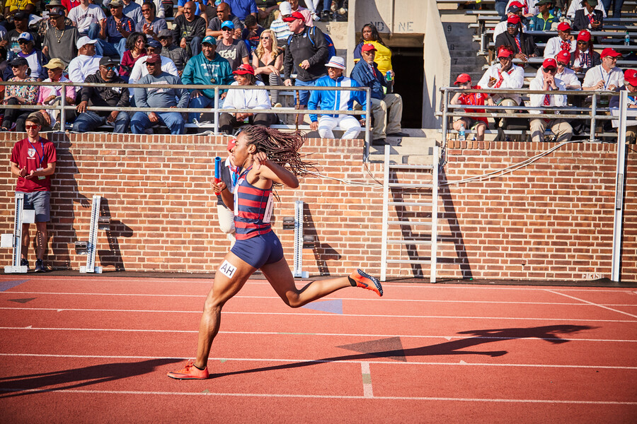 Uchechi Nwogwugwu runs in a meet while holding a baton.