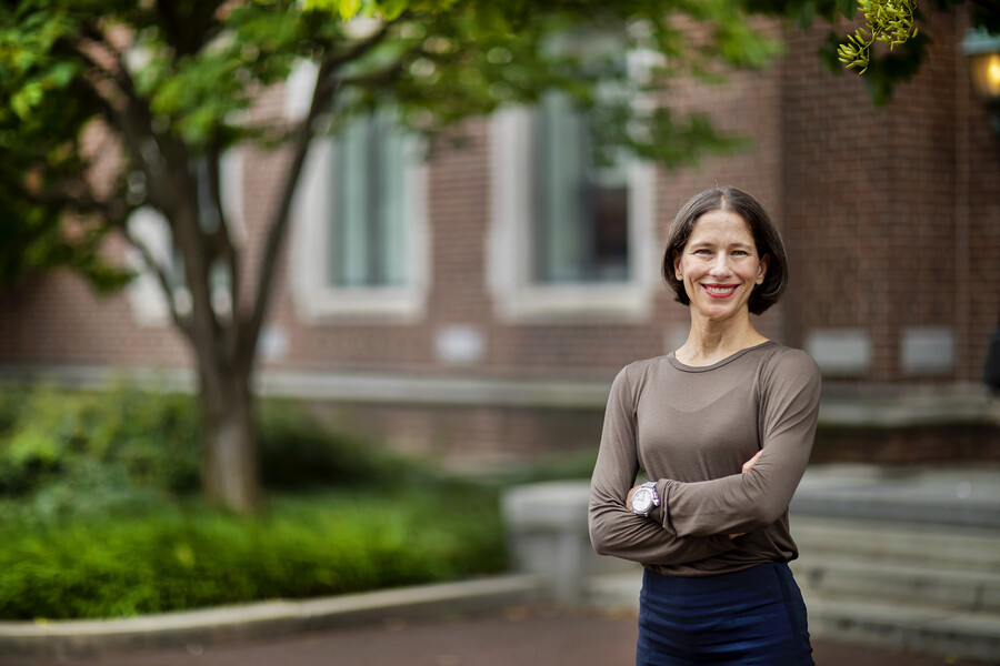 A smiling woman stands in front of a building