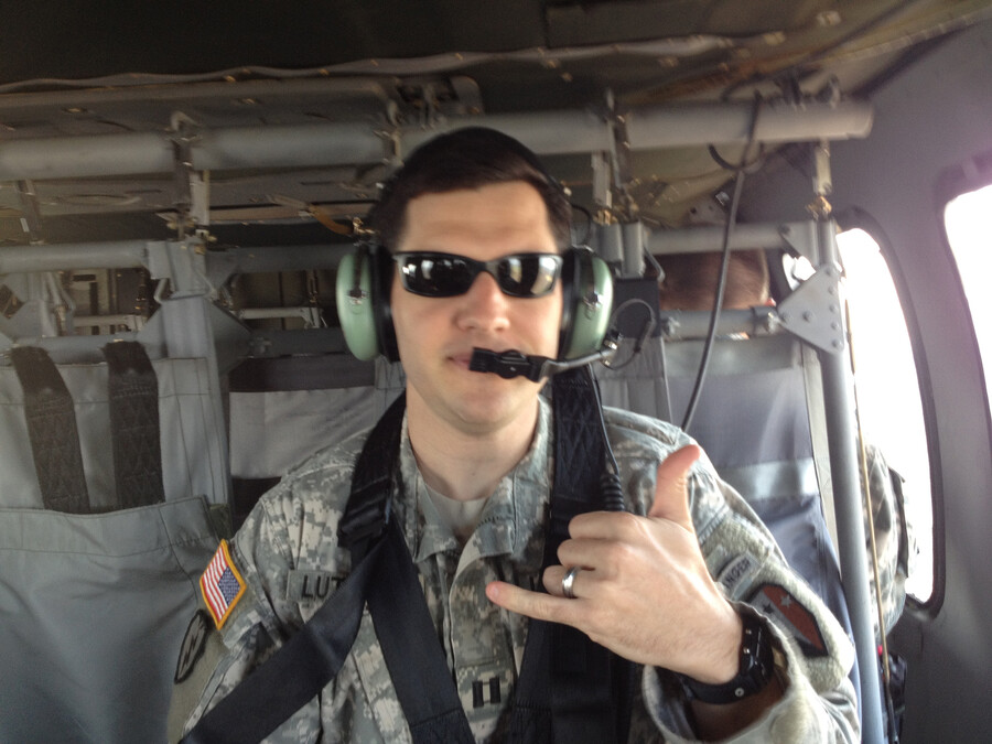 Greg Lutmann flashes a hand sign while strapped into a helicopter.