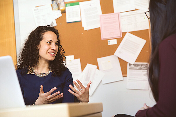 Sharon Wolf gesturing with her hands speaking to someone in an office.