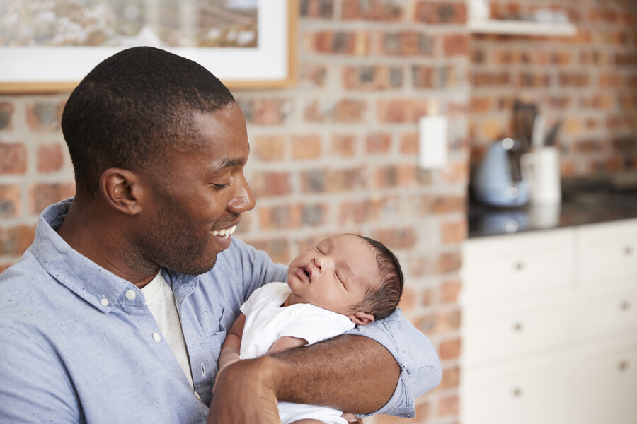 Parent at home with newborn in their arms.