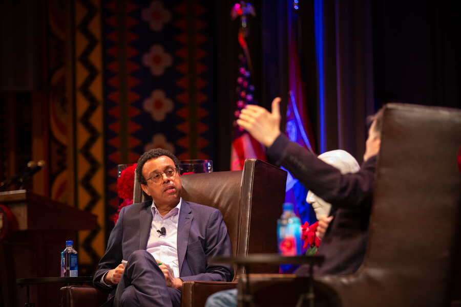 Wendell Pritchett seated on stage listening to Ken Burns speak.