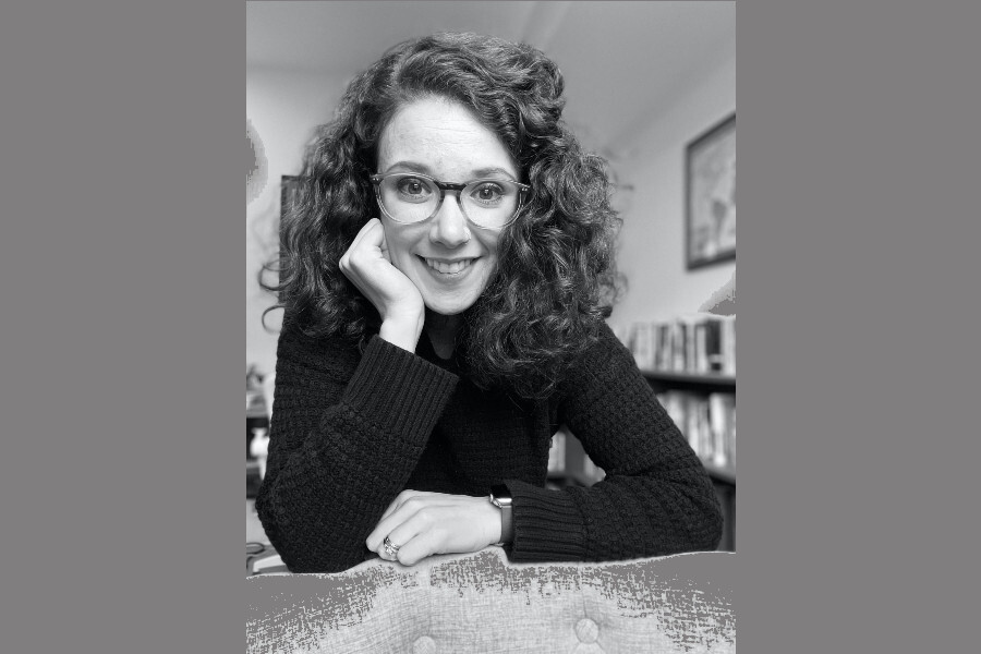 Black-and-white photo of Lacey Wade sitting at a desk, with her head propped up on one arm.