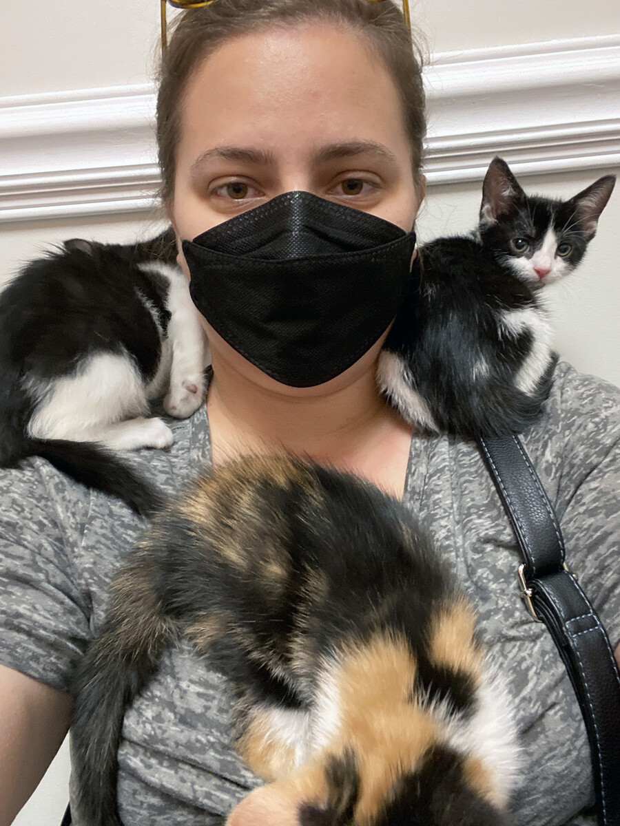 Heather Kostick with three kittens nestled on her body.