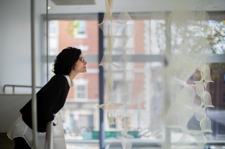 Laia Mogas-Soldevila leans over a railing to smell a hanging display at the ICA.