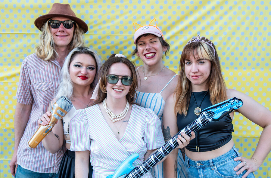 A group of people posing and smiling in front of a polka dot backdrop.