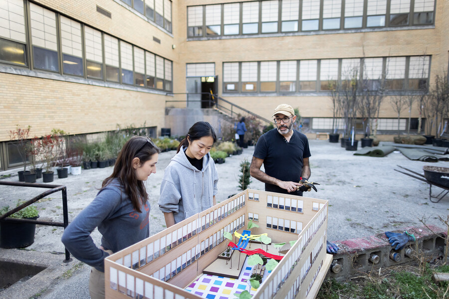 Three people looking at a model of the Breathing Room in the courtyard space.