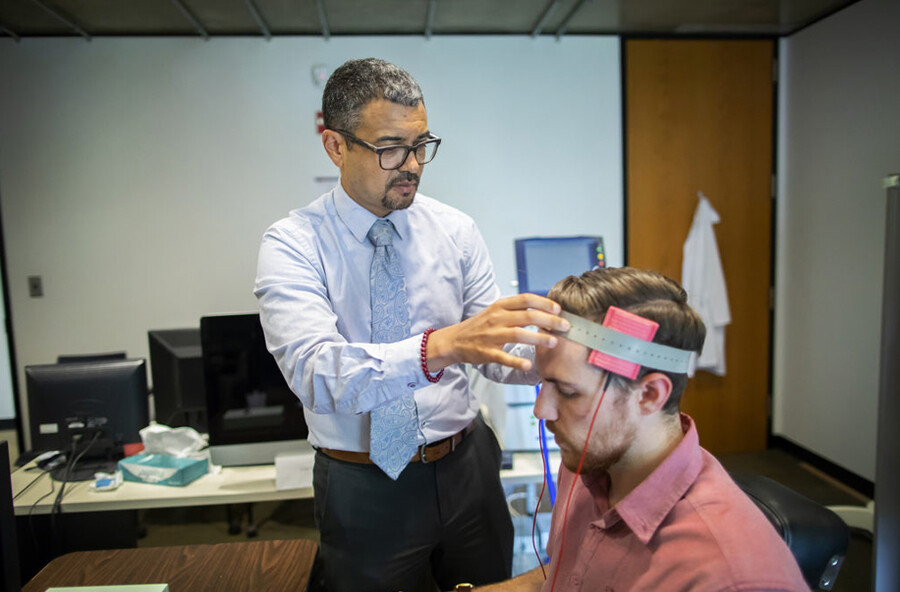 Roy Hamilton adjusts a transcranial electric stimulation device on a study participant.