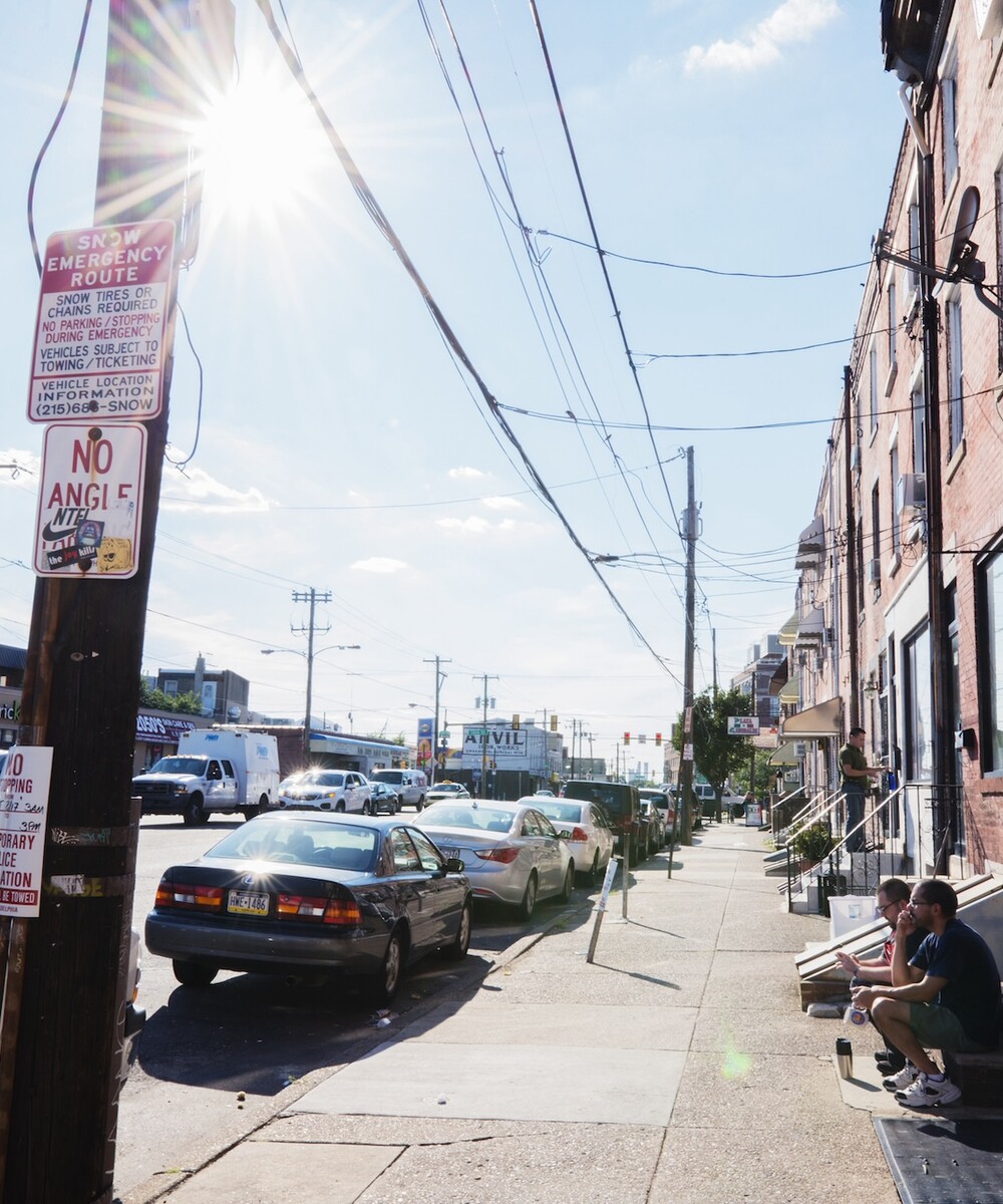Photo of two people sat on a porch facing traffic in Phialdelphia.