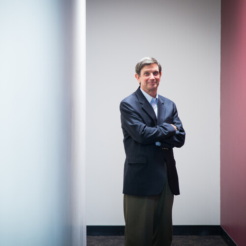 Person stands with arms crossed looking at the camera.