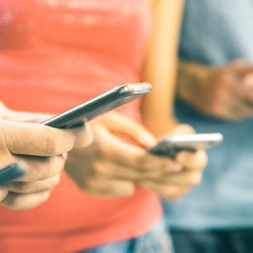 Four people stare at their smartphones.