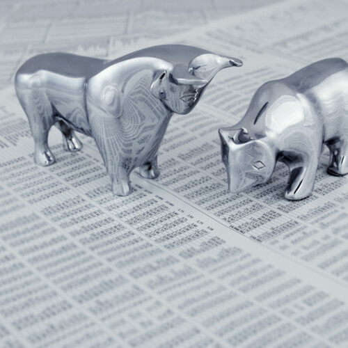 silver bull and bear figurines on top of a newspaper stock market section