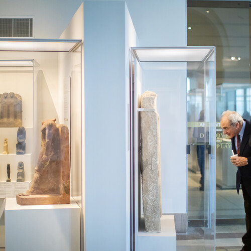 Two men looking into a display case with Egyptian artifacts. 