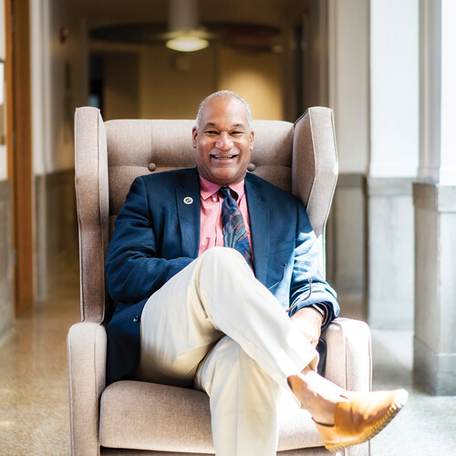 Herman Beavers sits in a recliner in a University hallway