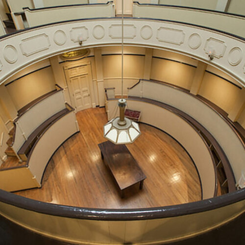 a circular room with a lamp and a table in the center