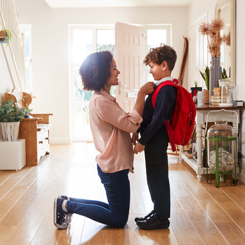 A parent helps dress a child before school